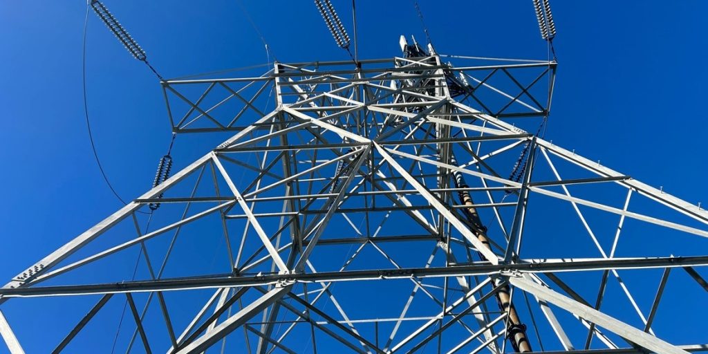A high-voltage transmission tower against a clear sky.