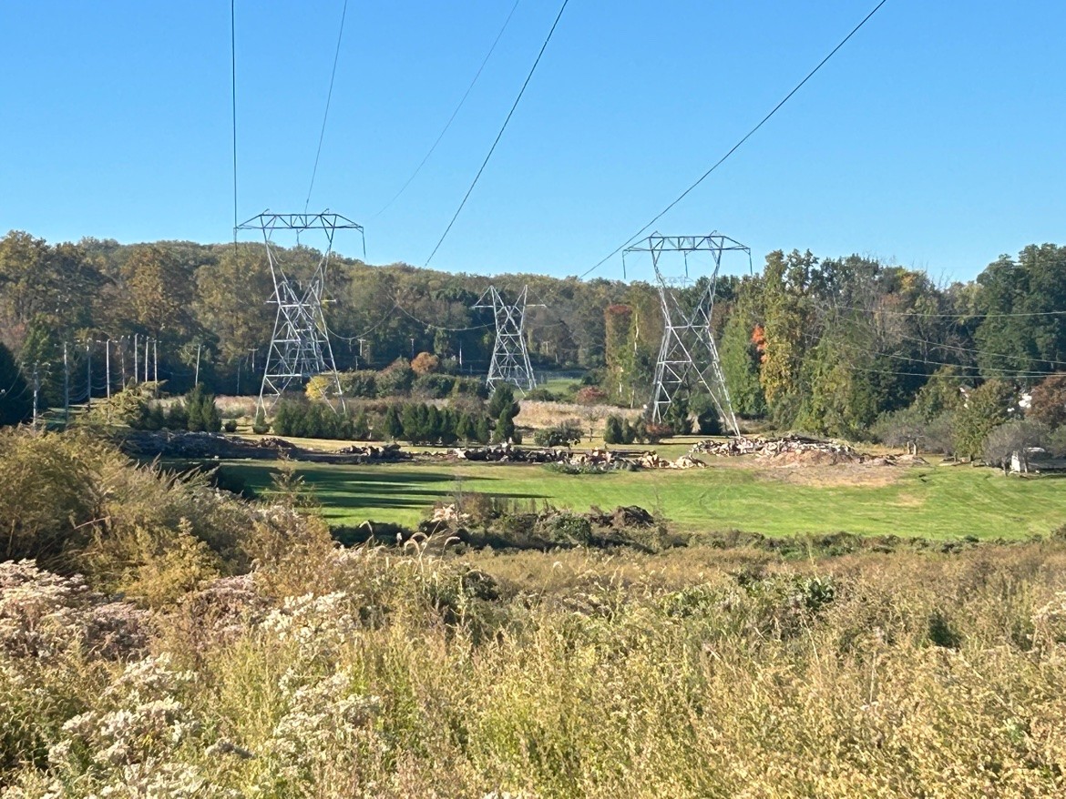 High-voltage transmission towers cross a field.
