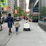 A delivery robot shares a sidewalk with pedestrians in Jersey City, New Jersey.