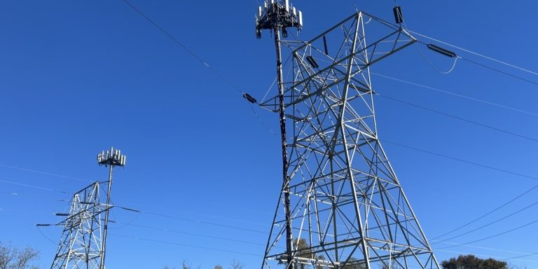 Electricity transmission towers with cell antennas against a blue sky in Chester County, Pennsylvania
